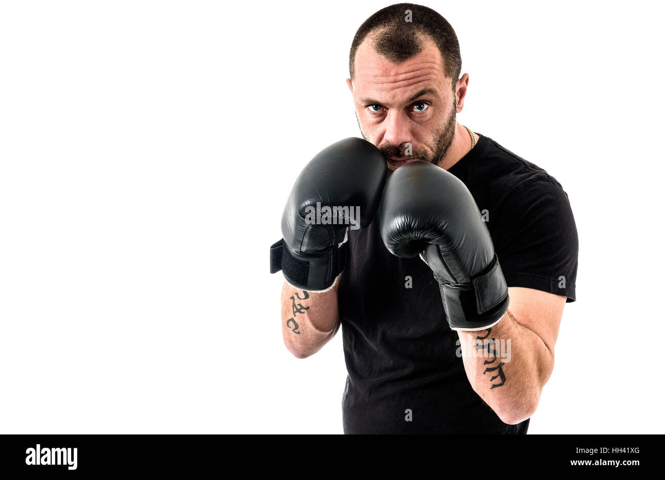 Retrato de atleta masculino boxer hombre mirando agresivo con guantes de boxeo, camisa negra y tatuajes. Aislado sobre fondo blanco. Foto de stock