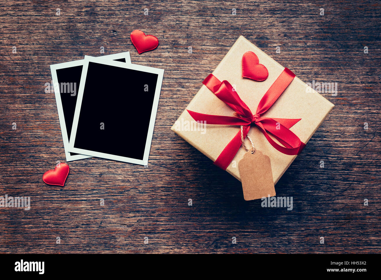 Marco de fotos en blanco y caja de regalo con corazón rojo sobre fondo de madera. Foto de stock