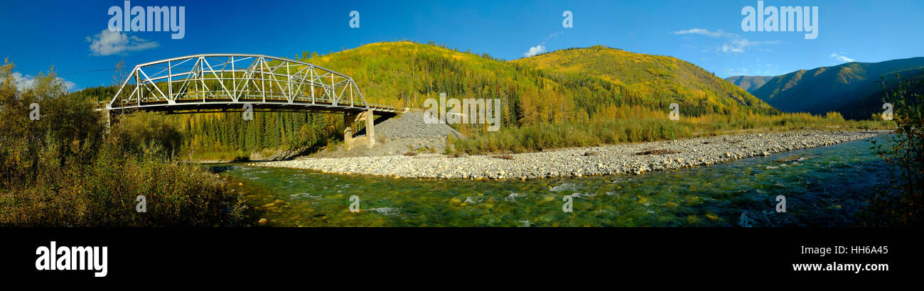 La autopista de Alaska puente que cruza el río. El río está ejecutando cristalinas aguas abajo de la vaalley. Colores de otoño en BC. Foto de stock