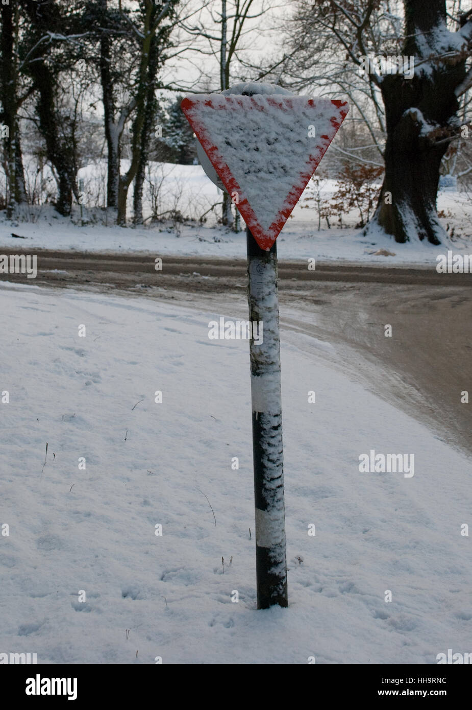 Señal de carretera cubierta de nieve con cruce cubierto de nieve Foto de stock