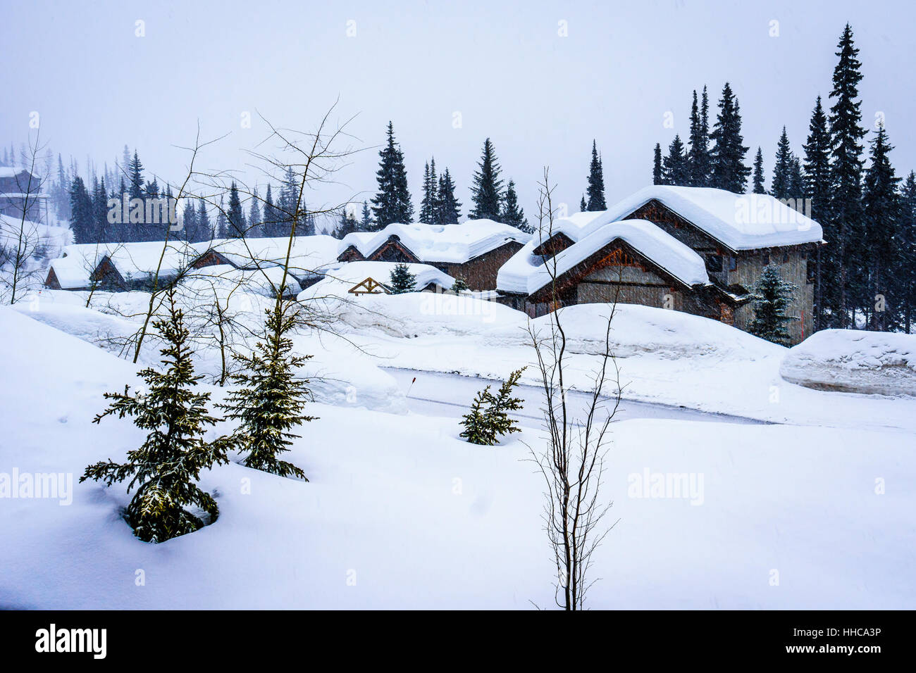 Paisaje invernal con techos cubiertos de nieve en la aldea alpina de Sun Peaks en las tierras altas del centro de Shuswap de British Columbia en Canadá Foto de stock