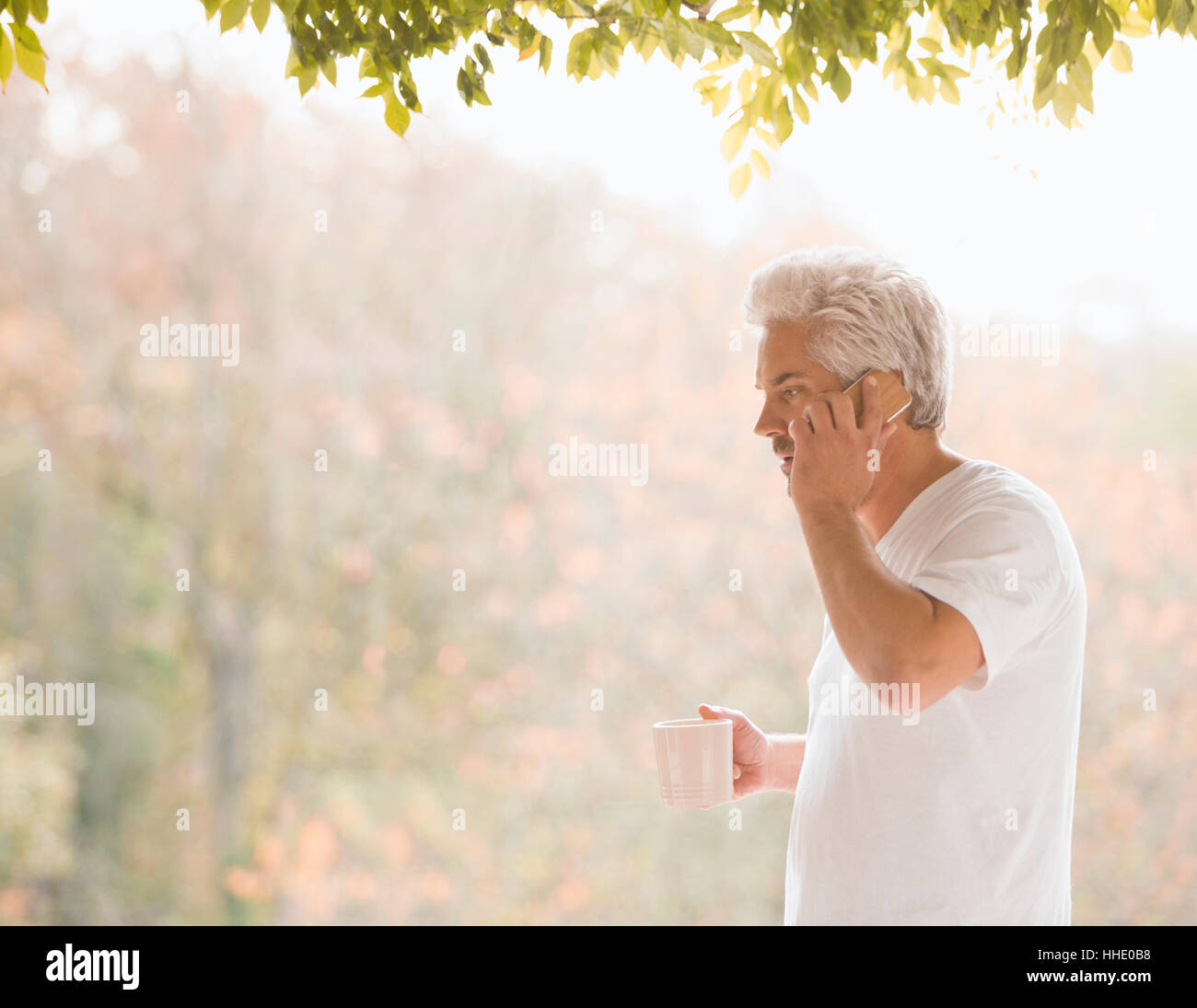 Hombre hablando por teléfono celular y el consumo de café en el patio de otoño Foto de stock