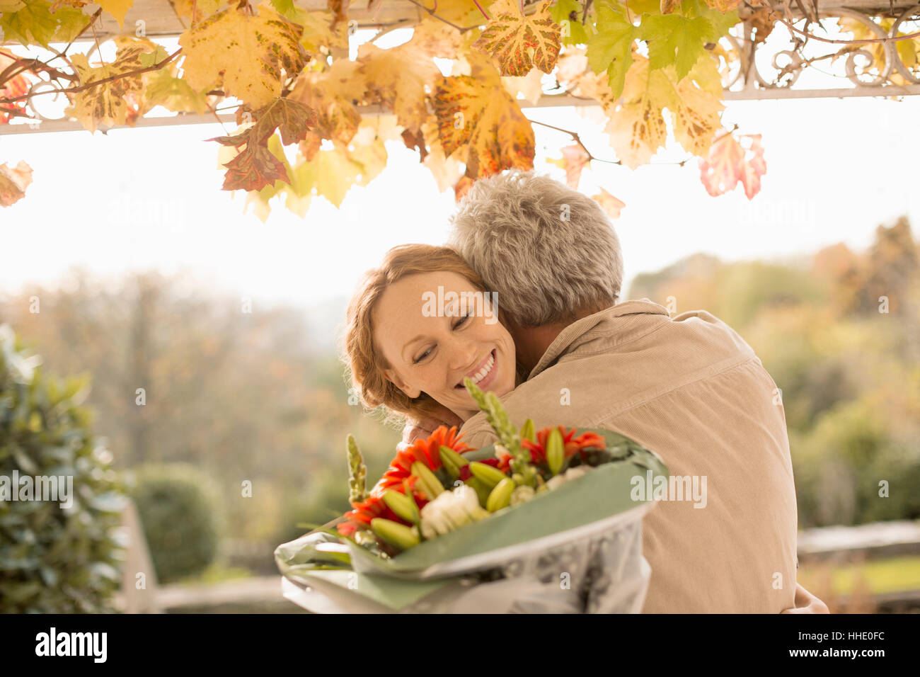 Marido sorprendente esposa con ramo de flores en el patio de otoño Foto de stock