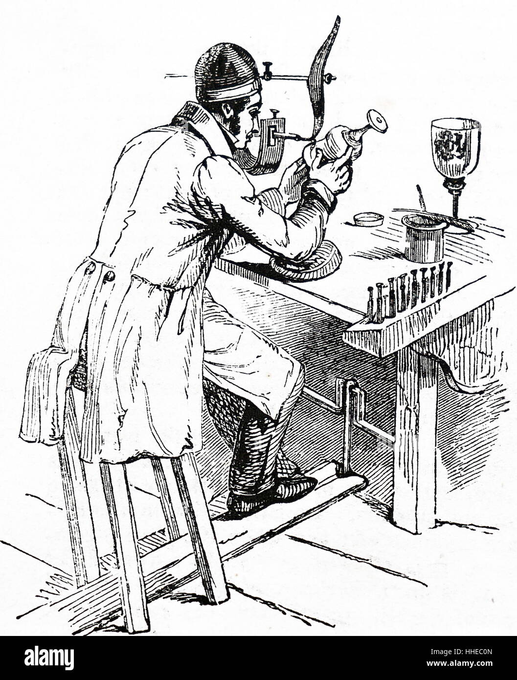 Un grabador de vidrio mediante un torno accionado por un pedal de font. En el banco a su derecha son los discos de encapsuladoras de diferentes diámetros, que junto con el esmeril humedecidos con aceite, fueron utilizados para grabar el vidrio. 1841 Foto de stock