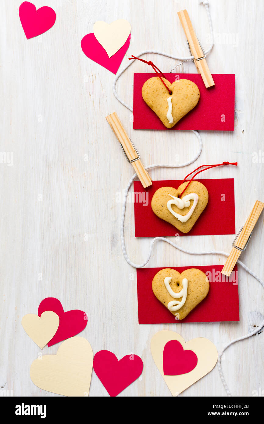 Corazones de papel en forma de corazón y cookies colgando de cuerdas con  mini vestidos pin por placa de madera blanca Fotografía de stock - Alamy
