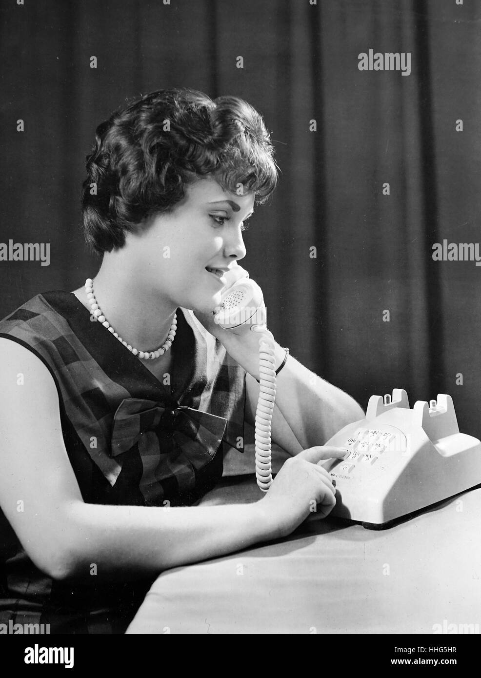 Un modelo experimental de un pulsador teléfono siendo desarrollado en los Laboratorios Bell Telephone es juzgado por Gayle Gerbe. El pulsador teléfono es factible hoy por los avances electrónicos que incluyen el transistor, inventado en los laboratorios Bell. Este pulsador particular diseño combina muchas características que promueven la máxima exactitud y que son preferidos por los usuarios. La disposición de botones es el resultado de meses de estudio de factores humanos. Foto de stock