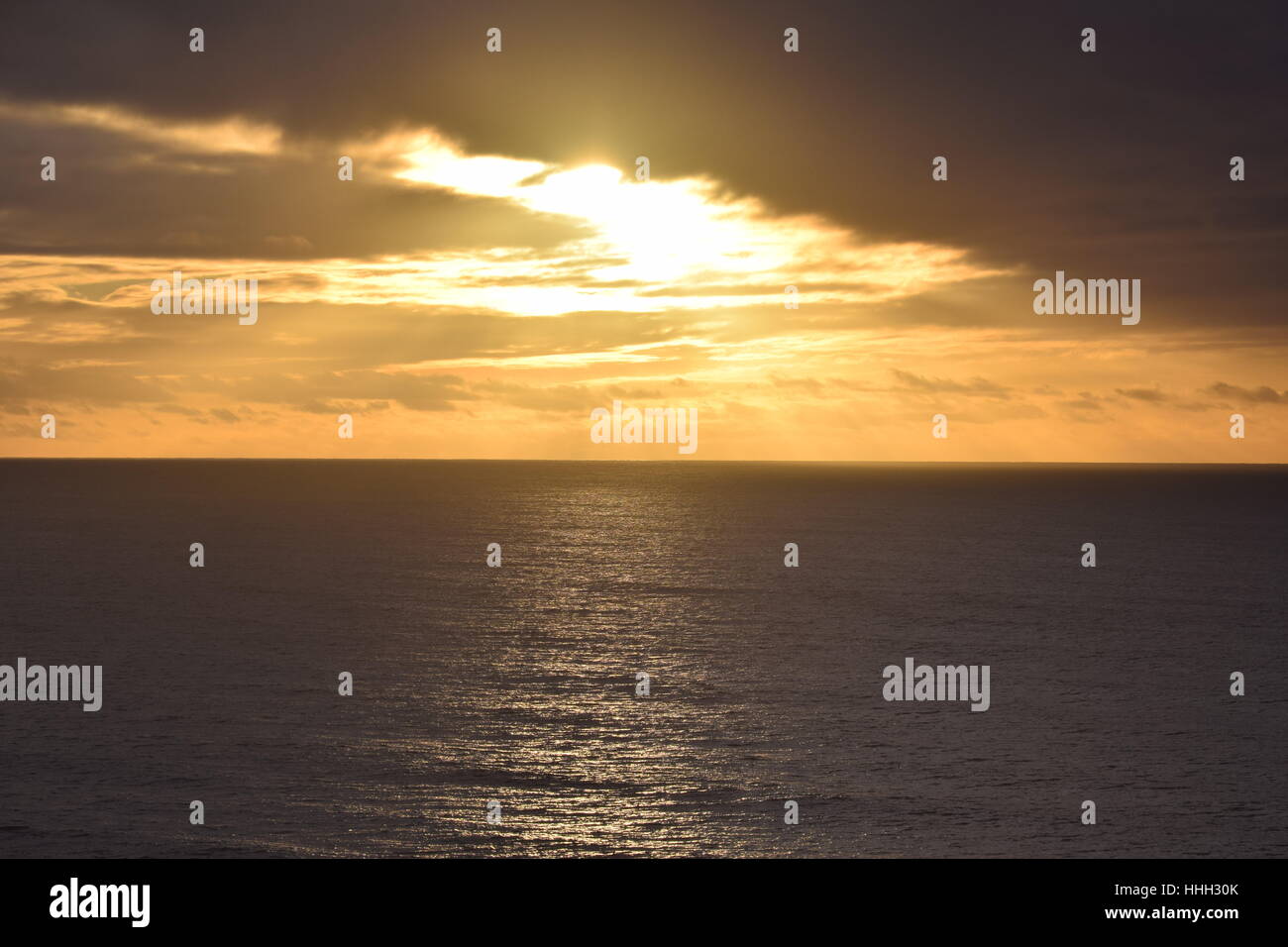 Sunset peeking a través de las nubes, la luz brillante en el océano Pacífico Foto de stock