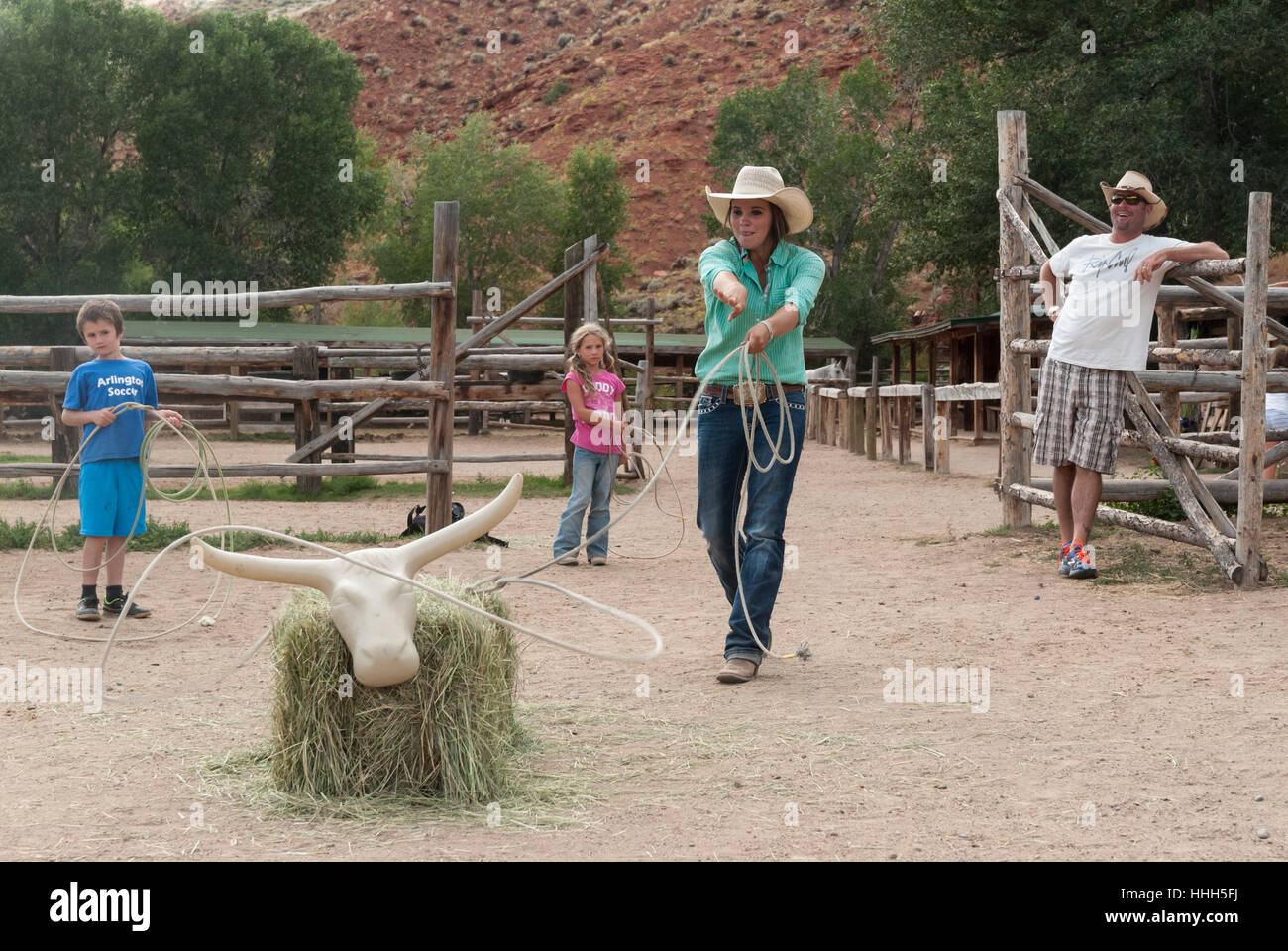 Roping práctica en el Lazy L&B rancho vacacional en Dubois, Wyoming: wrangler boleadoras una vaca paca de heno mientras los niños esperan su turno. Foto de stock