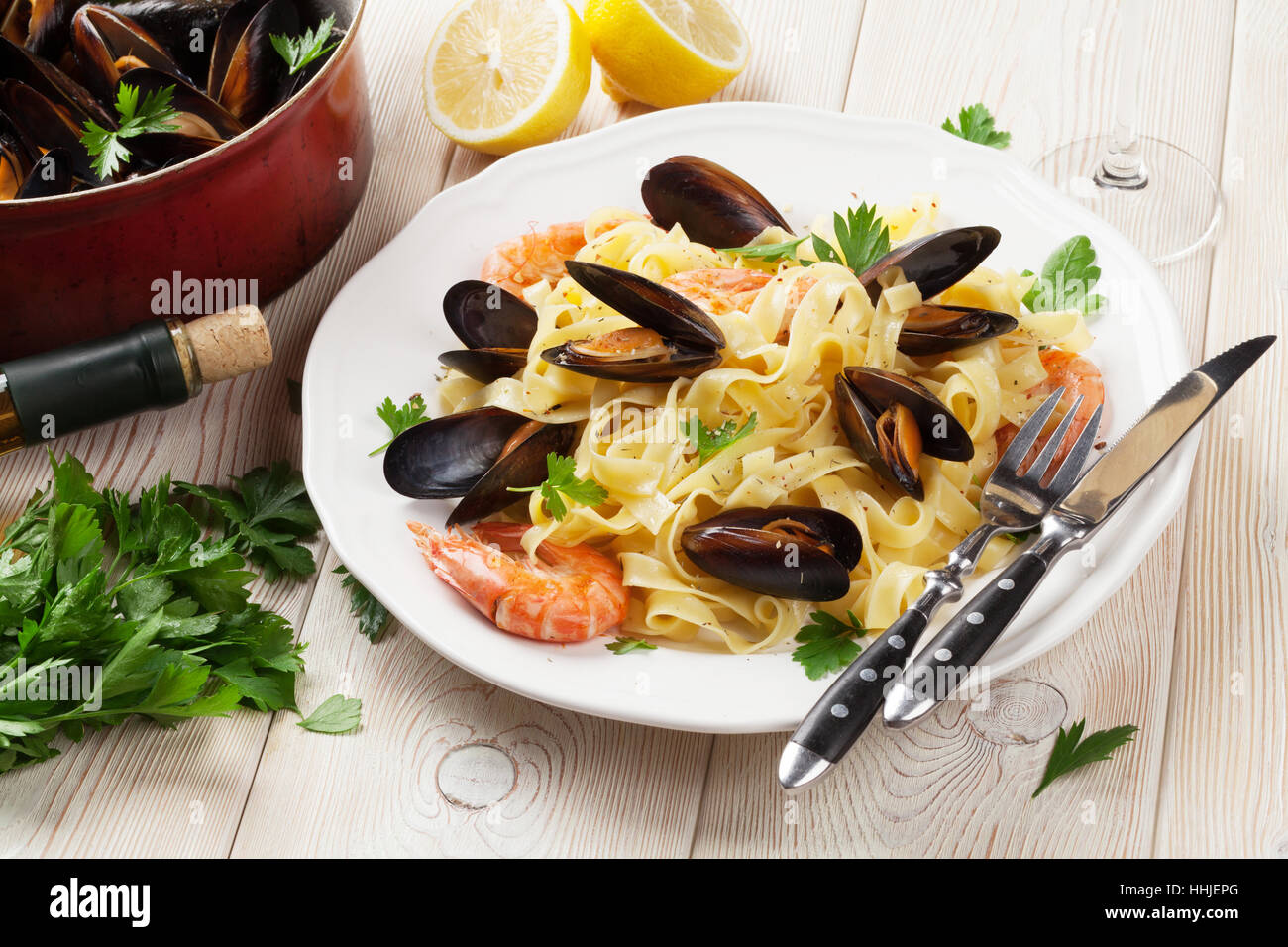 Pasta con marisco y vino blanco sobre la mesa de madera. Mejillones de roca y gambas Foto de stock