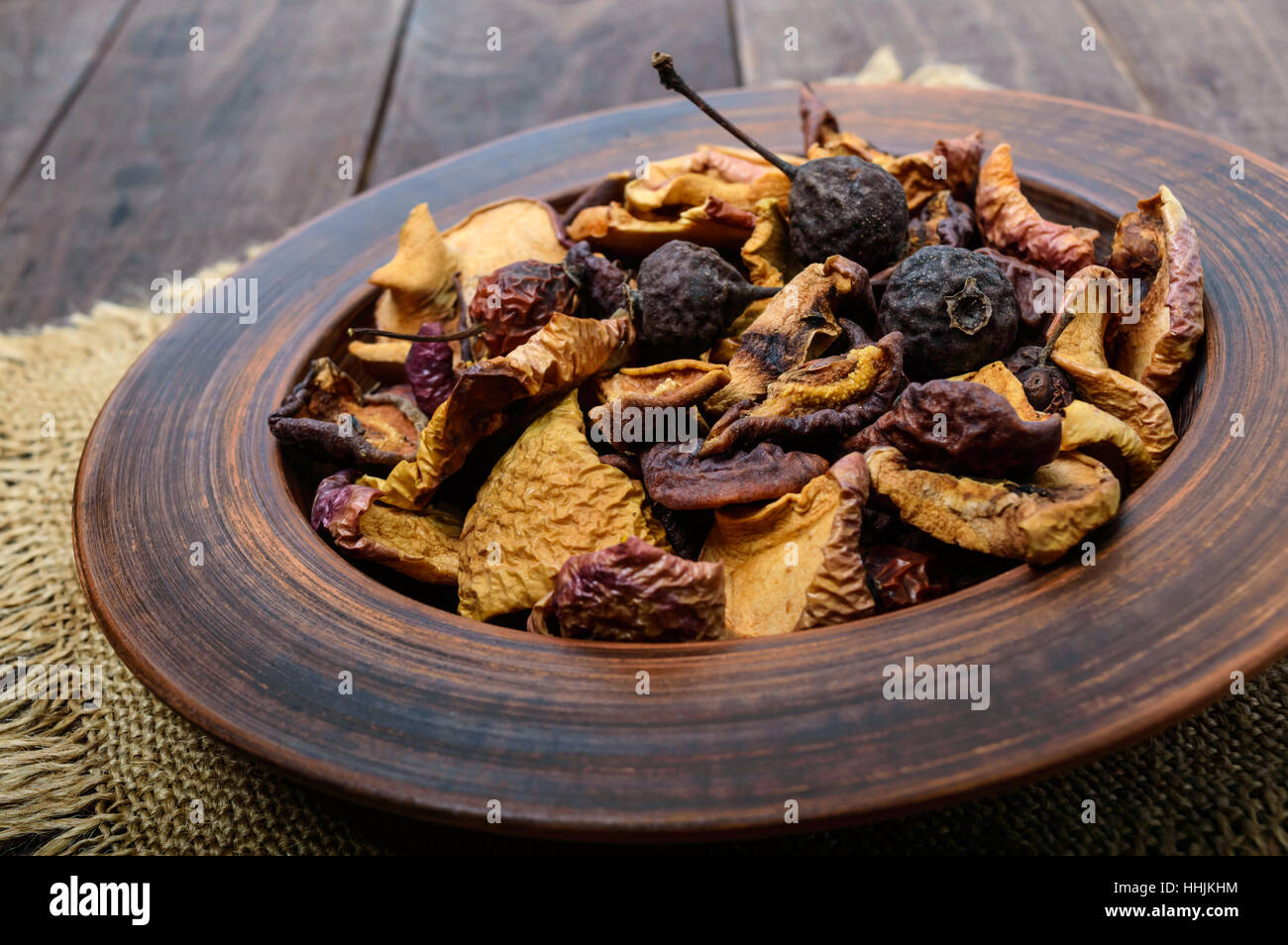 Los frutos secos (manzanas, peras, albaricoques), bayas en un recipiente de madera oscura de fondo. Cerca. Ingredientes para el invierno vitamina bebida, compota. Foto de stock