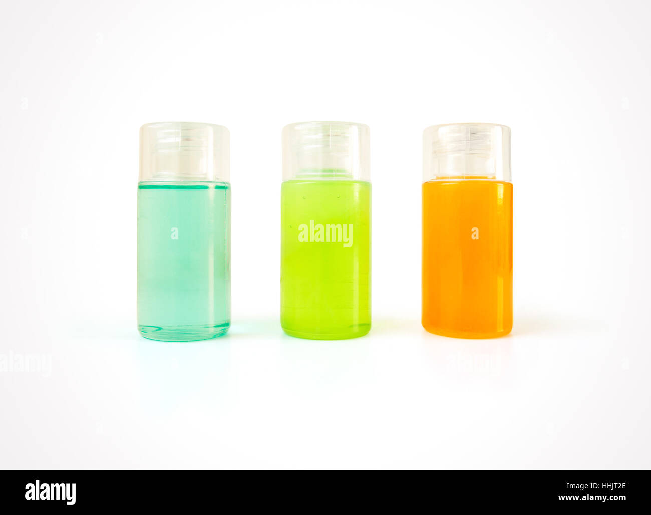 Tres pequeñas botellas de plástico llena de coloridos productos cosméticos con espacio de copia. Productos de belleza y cuidado corporal para baño en contenedores en blanco Foto de stock
