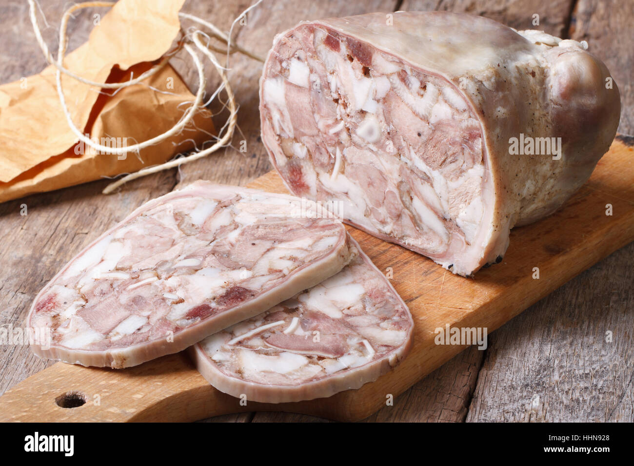 Cortar headcheese sobre una tabla de cortar horizontal cerca. Foto de stock