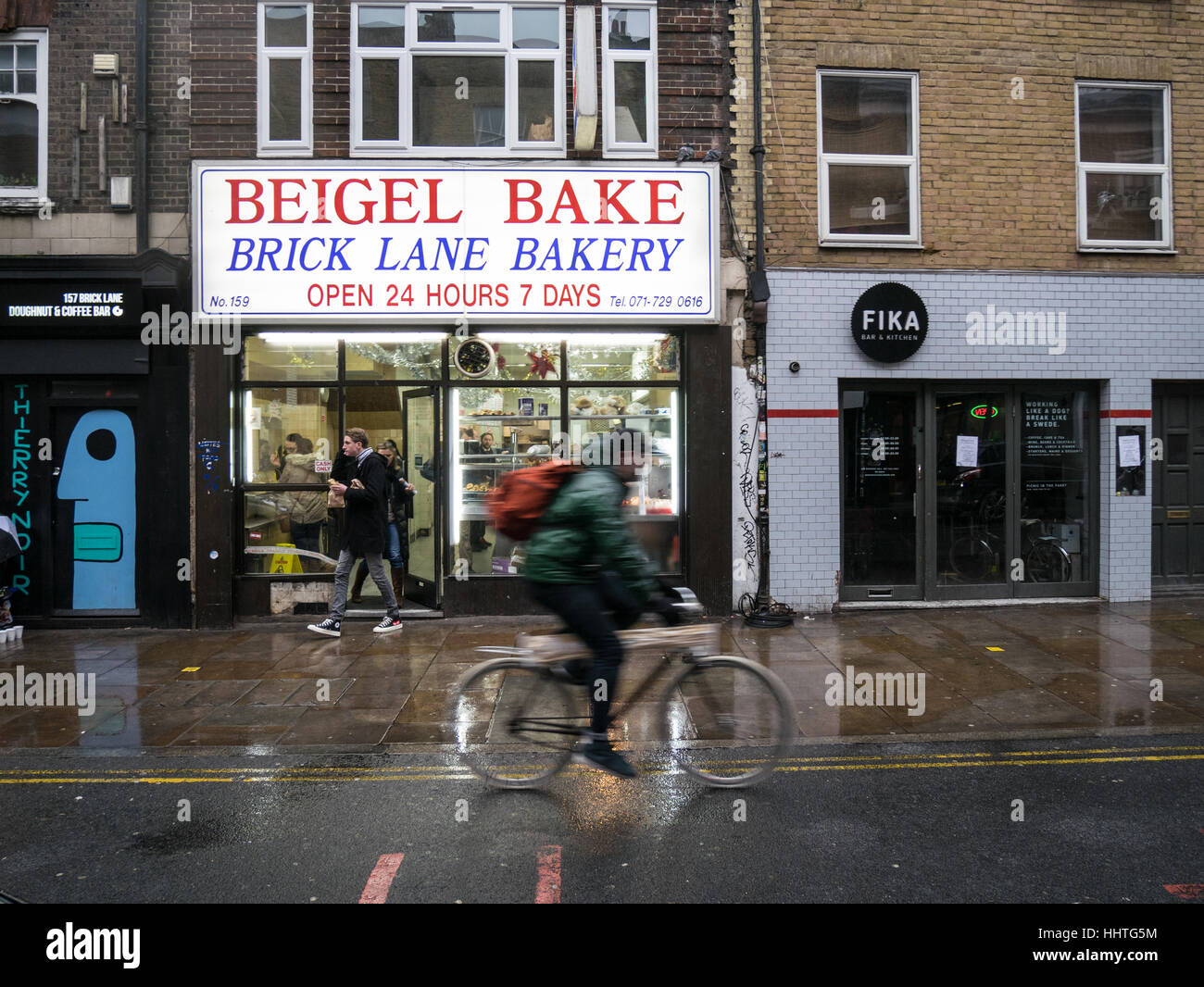 Tienda Beigel Brick Lane - tienda de bagels un ciclista paseos el pasado 24 horas Panadería Beigel en London's Brick Lane Foto de stock