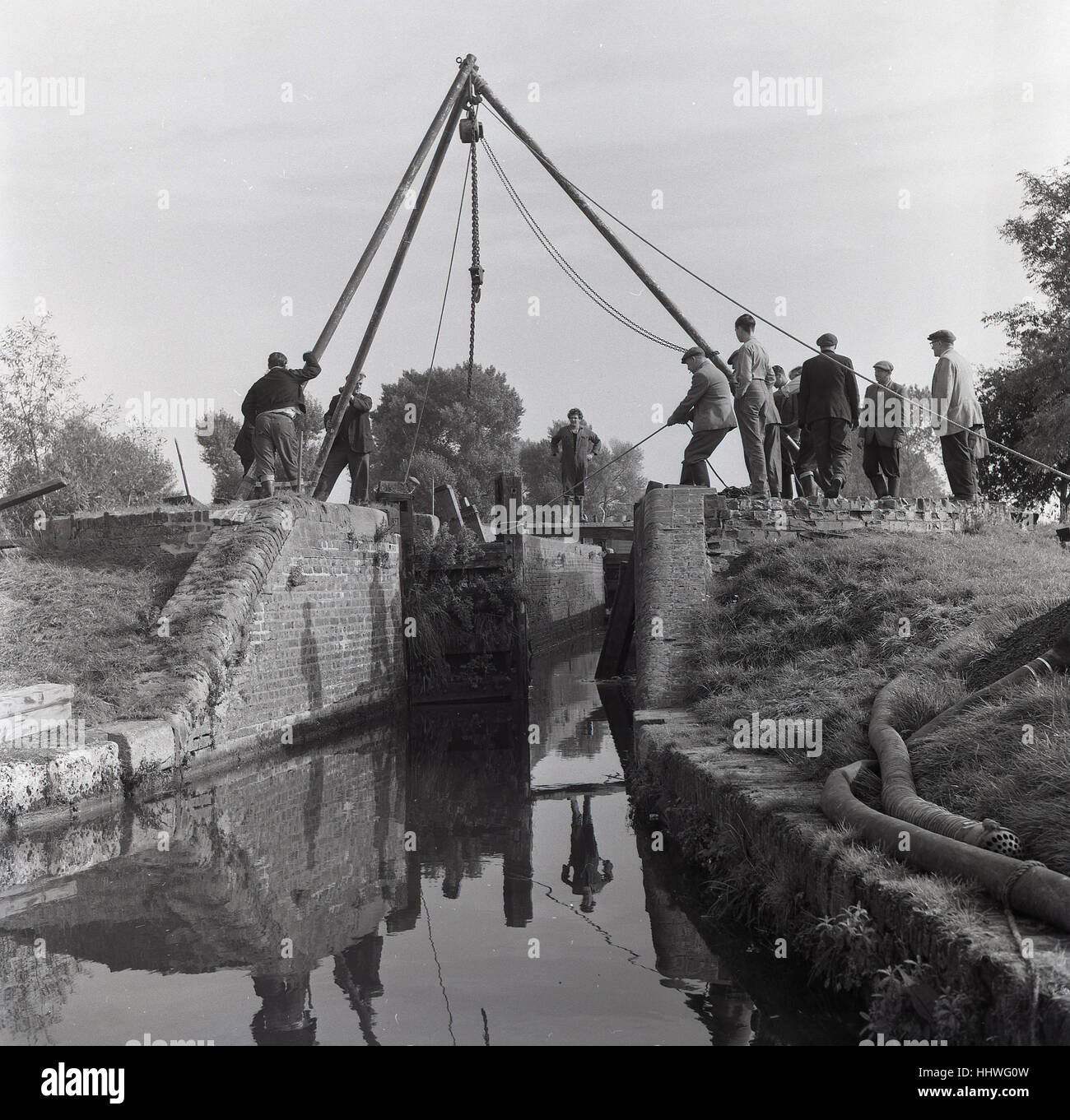 1960, histórico, un equipo de hombres trabajando en las reparaciones de una compuerta de esclusa de un canal, Inglaterra, Reino Unido. Foto de stock