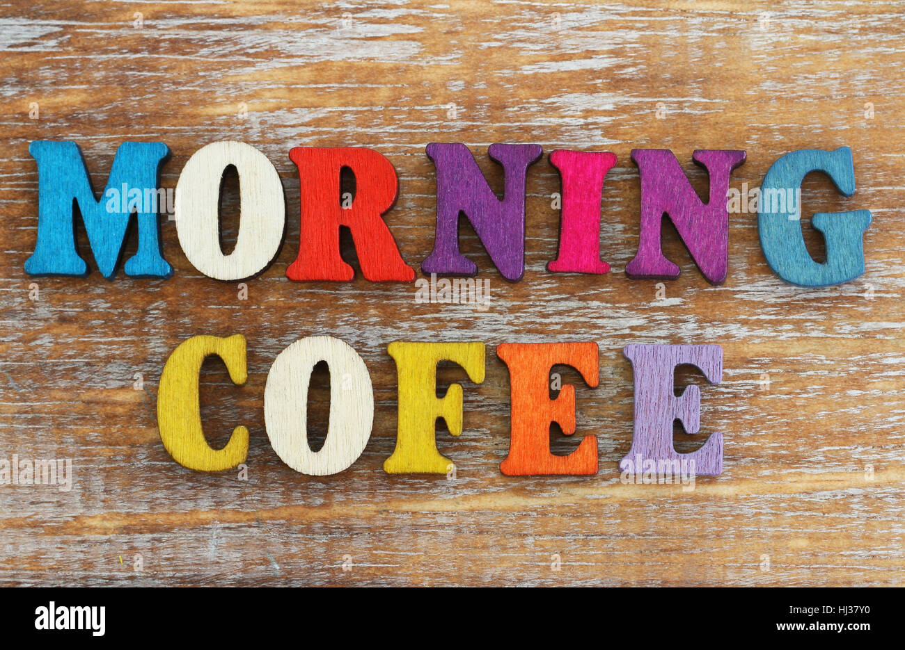 El café de la mañana ha escrito con letras de colores sobre la superficie de madera rústica Foto de stock