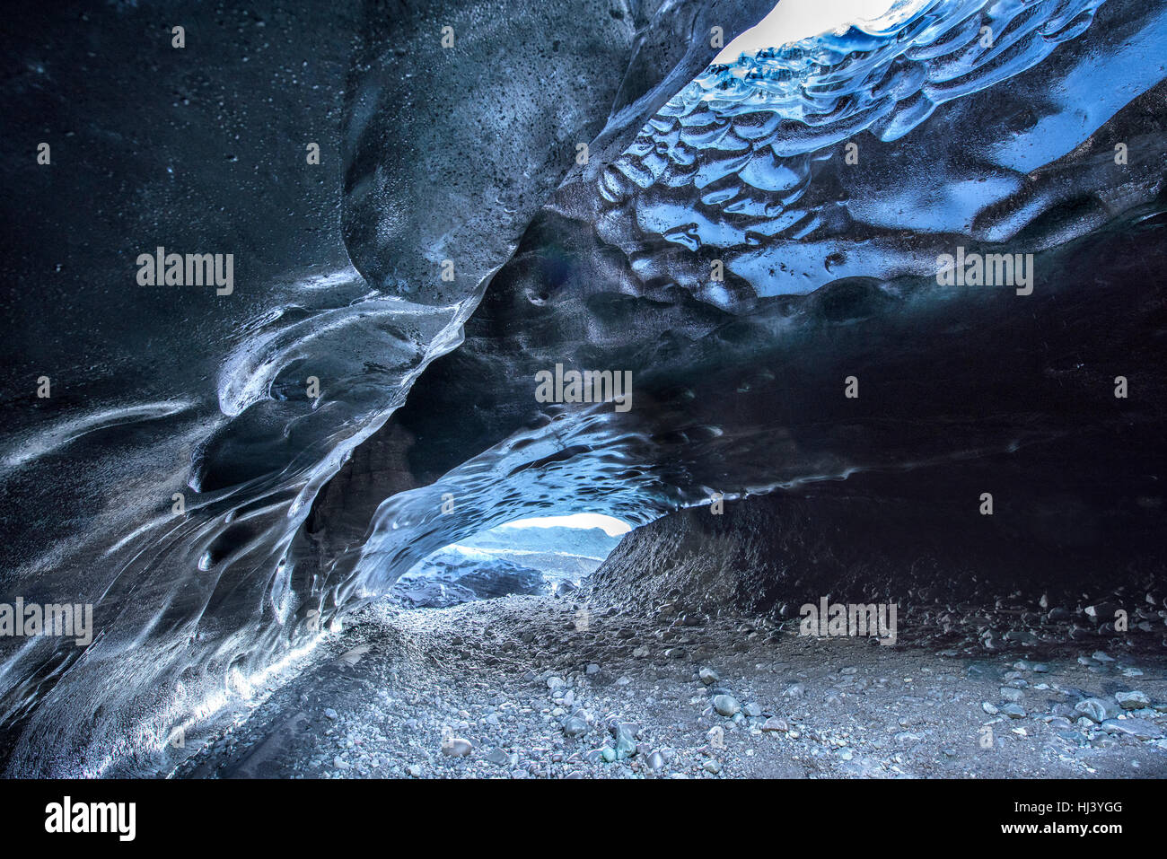 Una cueva de hielo volcánico en Islandia toma el color de la tierra negra de origen volcánico que rodean el glaciar desde que se formó la caverna. Foto de stock
