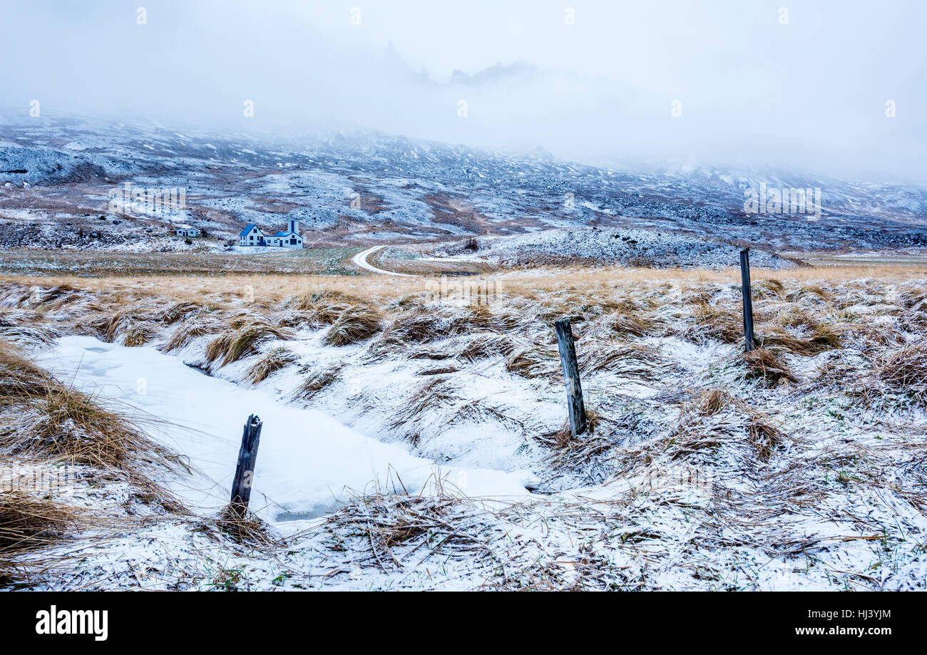 Un resfriado, una escena de nieve en Islandia muestra un río congelado y helado paisaje de pasto durante un día de invierno. Foto de stock