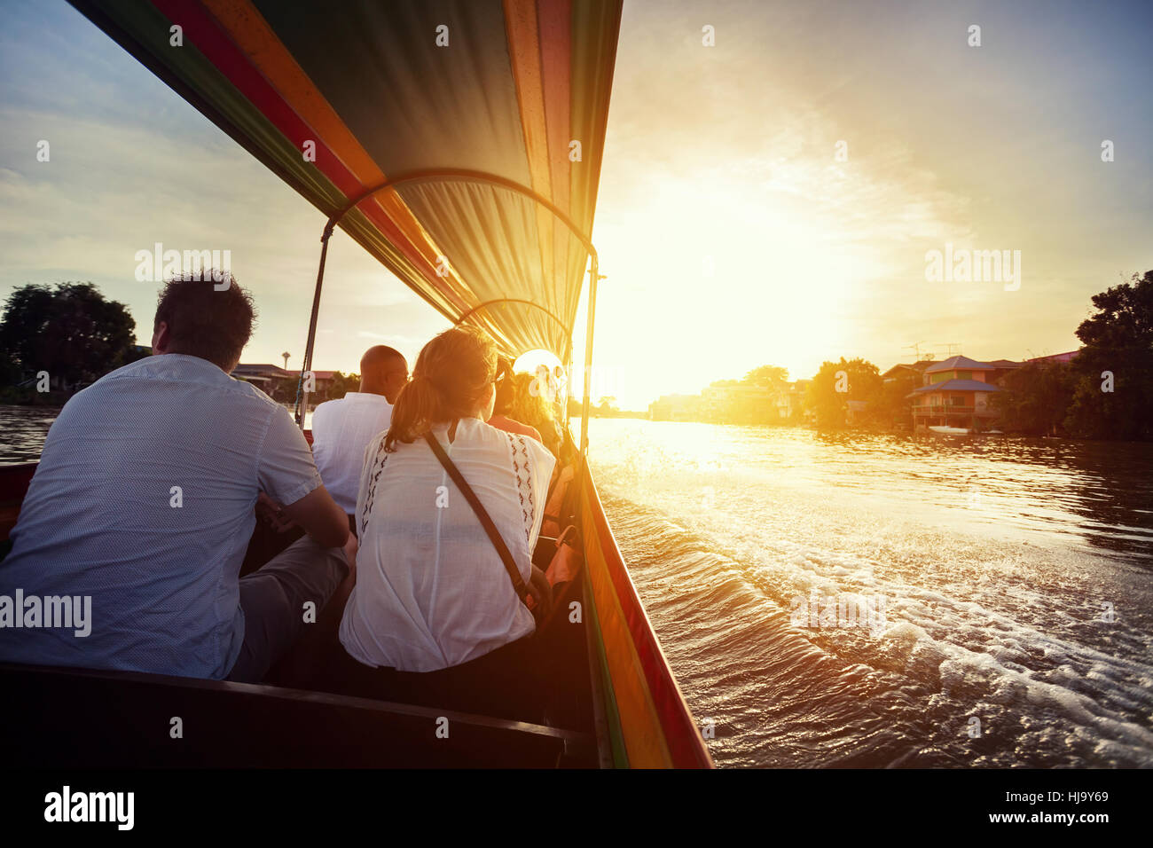 Turista sentado en bote de cola larga crucero por el río Chao Phraya en la antigua ciudad de Ayutthaya, al atardecer, Tailandia Foto de stock