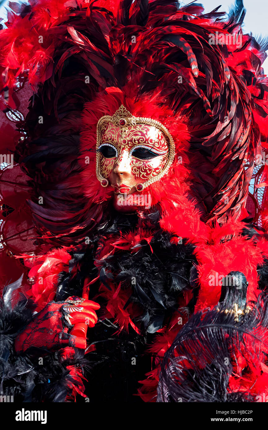 Participante en un colorido traje rojo y máscara tradicional durante el famoso Carnaval de Venecia, Italia. Foto de stock