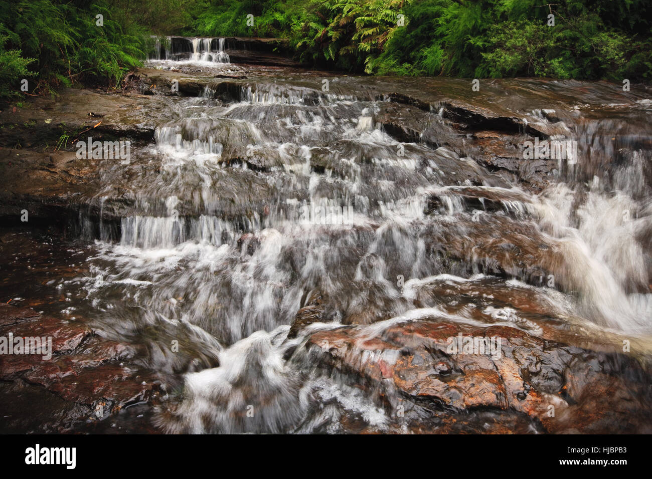Cascada de agua sobre las piedras en un arroyo de montaña. Foto de stock