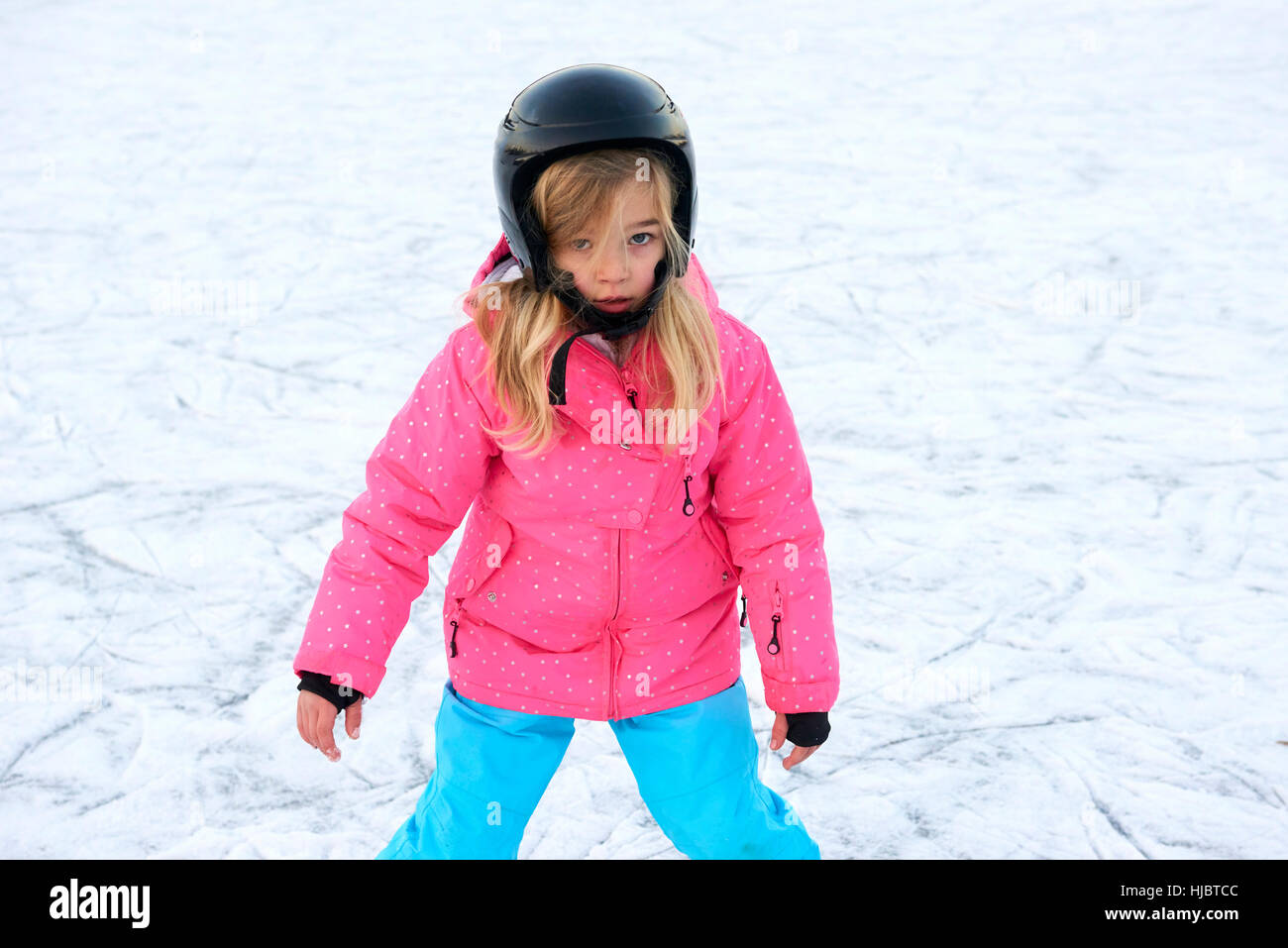 Poco feliz chica patinando en invierno afuera, vistiendo un casco de seguridad Foto de stock