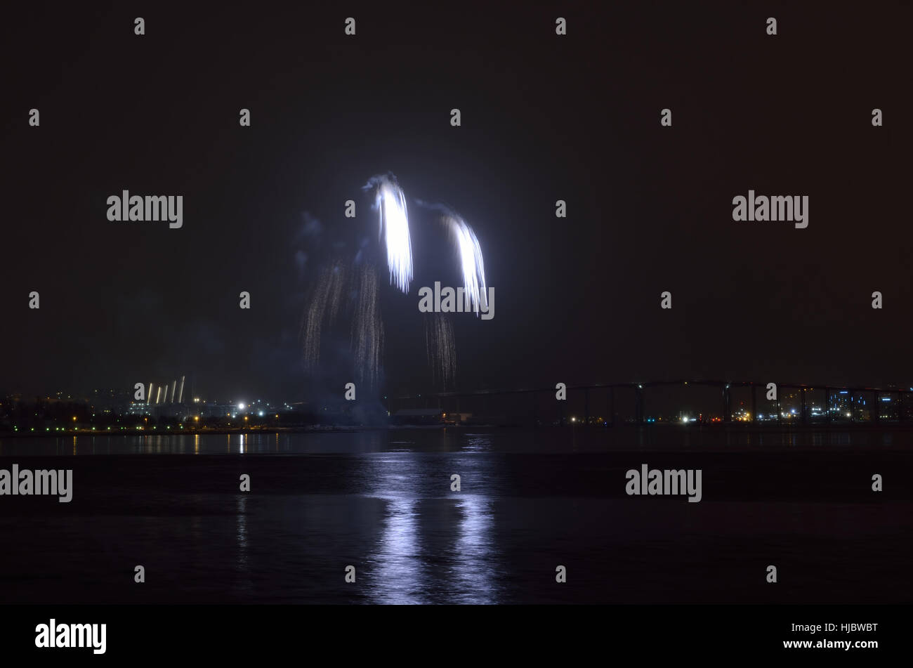 Hermosos fuegos artificiales en el cielo nocturno de la ciudad de tromsoe con puente, catedral y colorido reflejo en el fiordo de superficie de agua fría Foto de stock