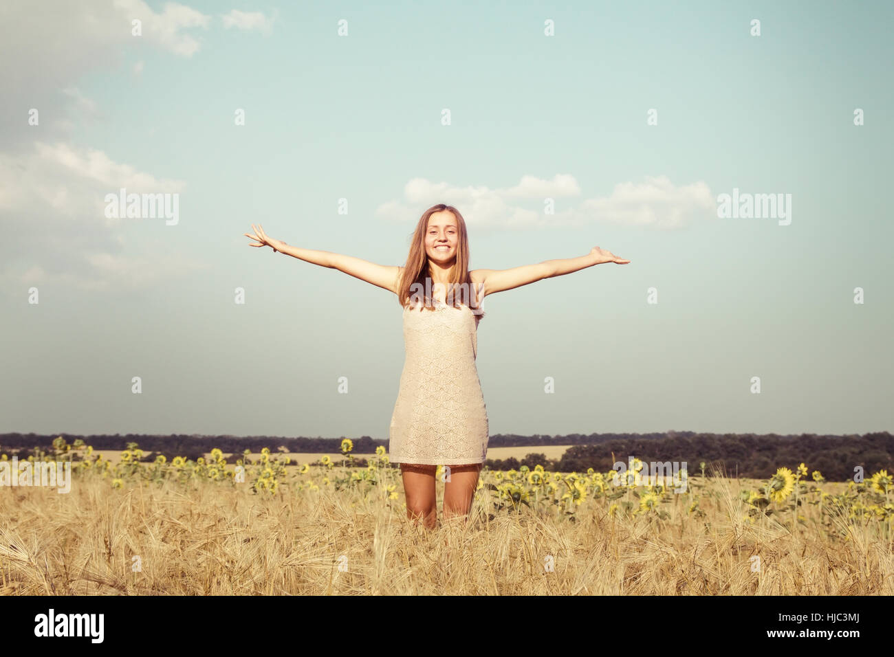 Hermosa mujer joven saltando y bailando en campo amarillo, piscina de verano Foto de stock