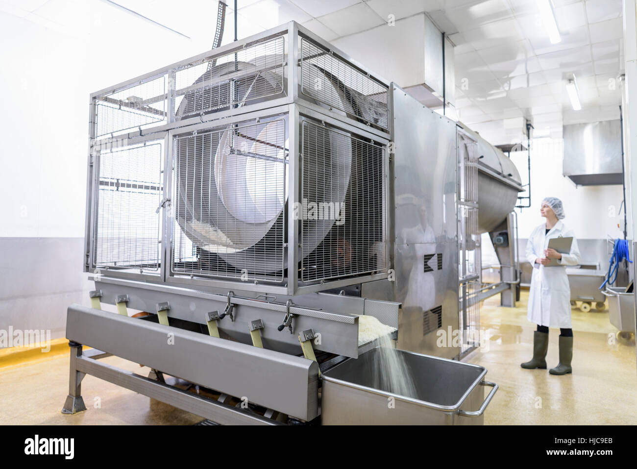 Trabajador con máquina de cocción de arroz de Asia en la fábrica de alimentos Foto de stock