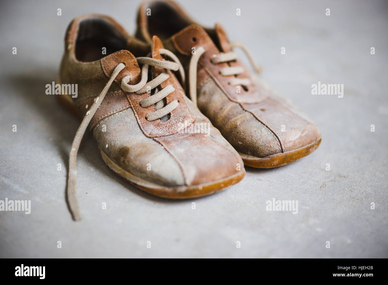 Antiguo grunge botas marrón sobre fondo de cemento gris Foto de stock