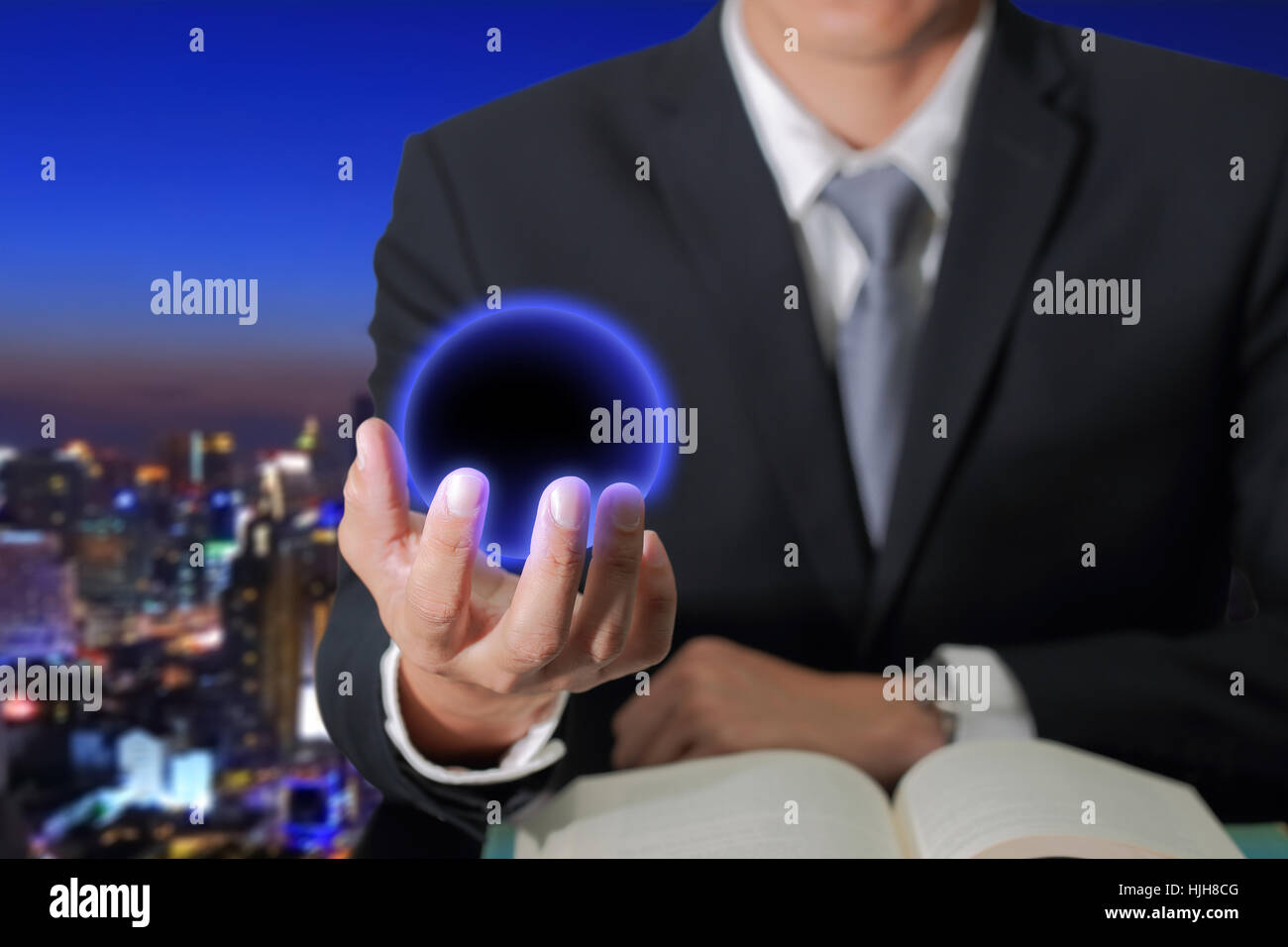 Hombre de negocios asidero bola azul oscuro sobre fondo ciudad de noche abstracta borrosa como concepto Innovación. Foto de stock