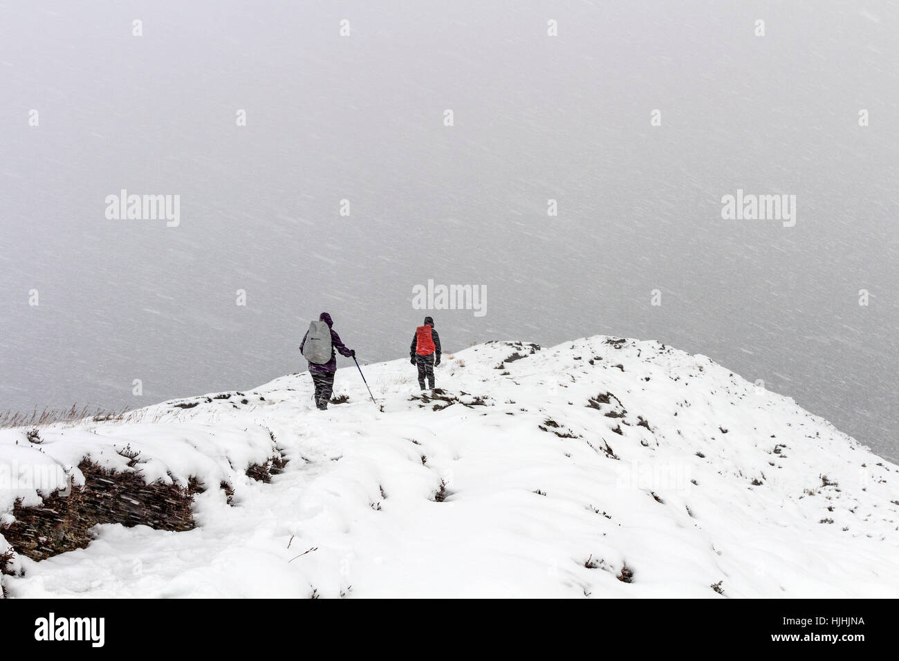 Los paseantes sobre la montaña de Barrow en el empeoramiento de las condiciones meteorológicas de Lake District Cumbria Reino Unido Foto de stock