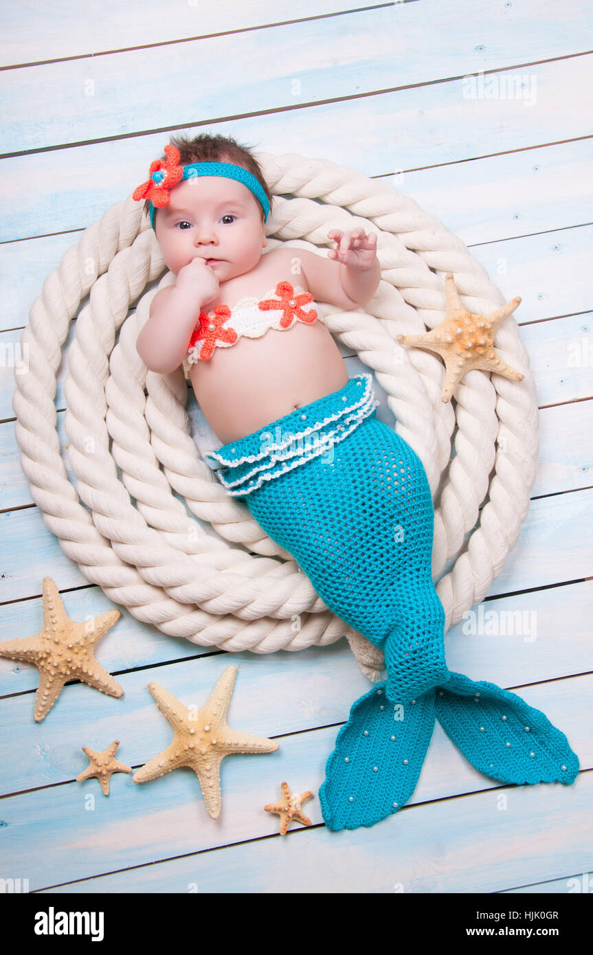 La niña recién nacida en un traje de sirena, reside en las cuerdas sobre  tablas de madera Fotografía de stock - Alamy