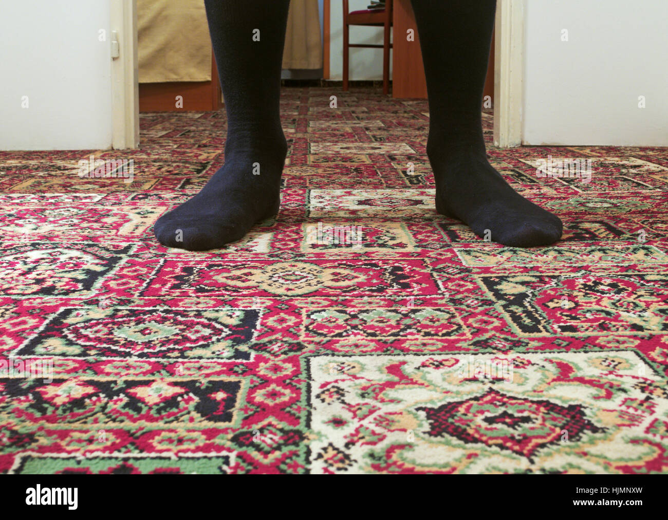 Hombre que llevaba calcetines sobre una alfombra permanente Foto de stock