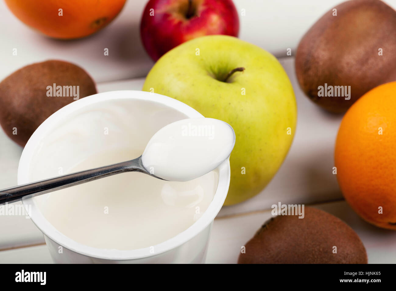 Cuchara con yogur y frutas sobre la mesa de madera blanca Foto de stock