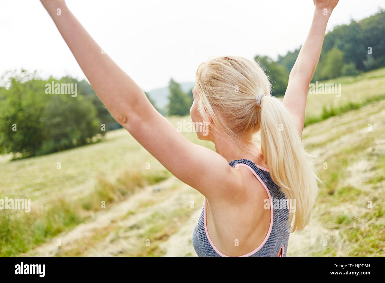 Mujer joven estirando los brazos en el aire como ejercicio de relajación wellness Foto de stock