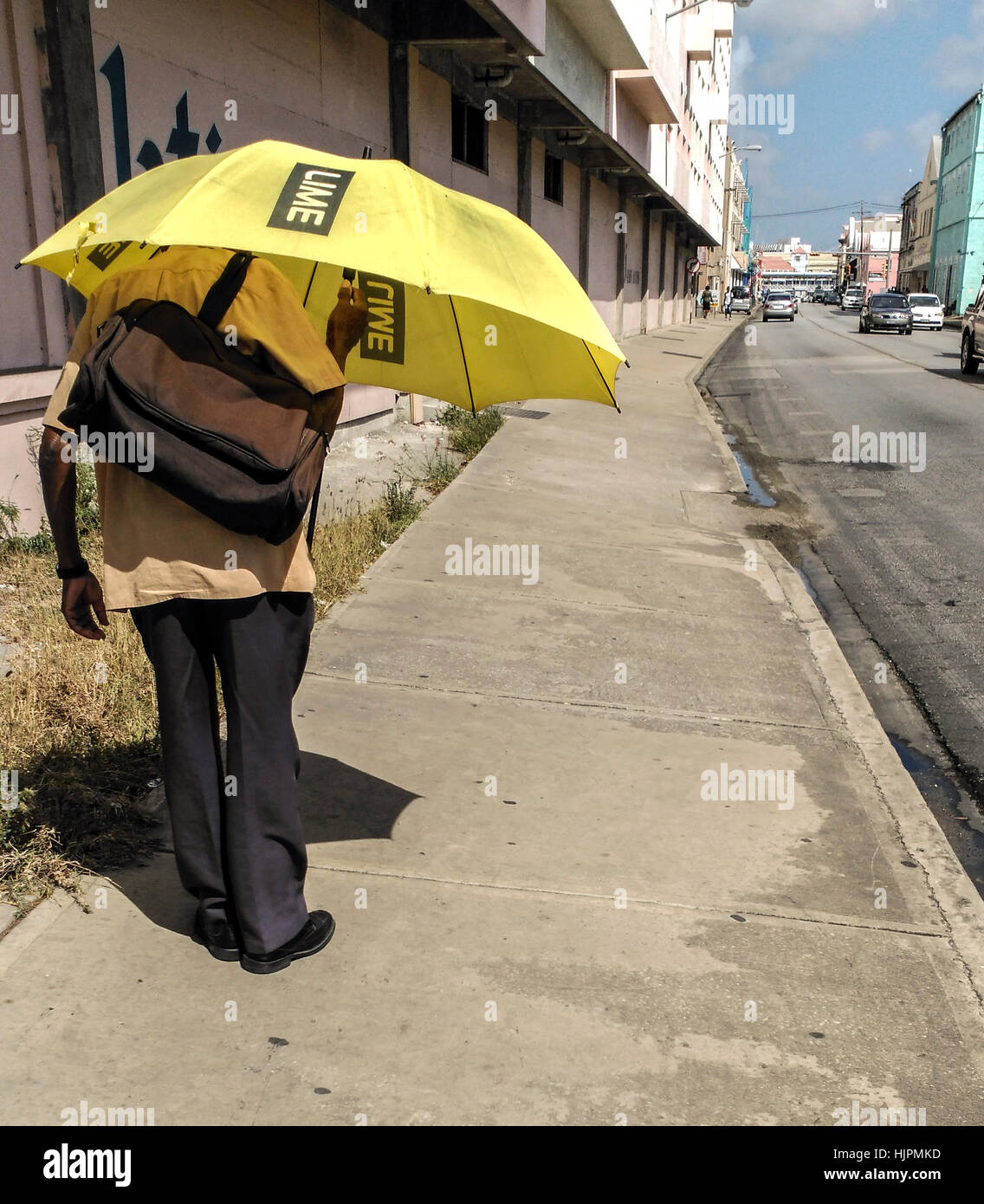 Barbados, país insular en las Antillas, Caribe: un hombre negro caminando por la calle sosteniendo un paraguas. Foto de stock