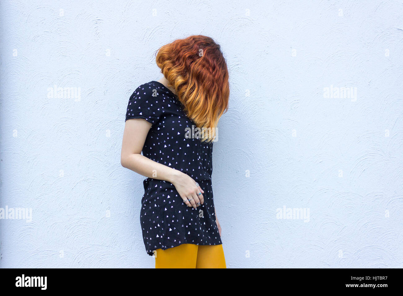 Jovenes Mujeres Caucasicas Con Pelo Corto Rojo Vestidos De Traje Negro Esta Contra La Pared Gris Con El Rostro Cubierto Fotografia De Stock Alamy