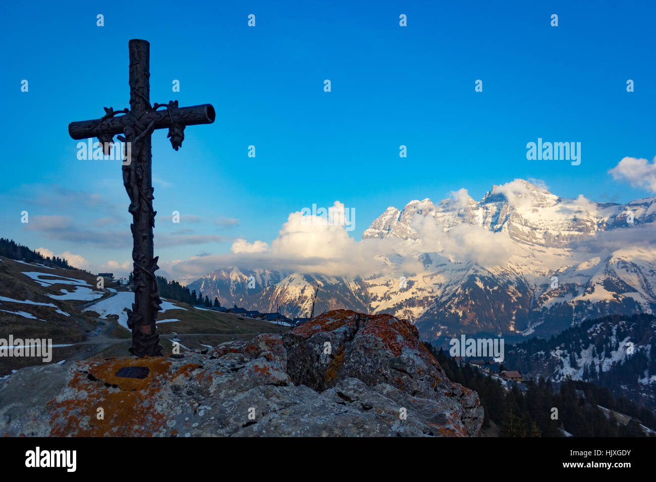 Cruz religiosas sobre una roca con vistas de montañas nevadas Foto de stock