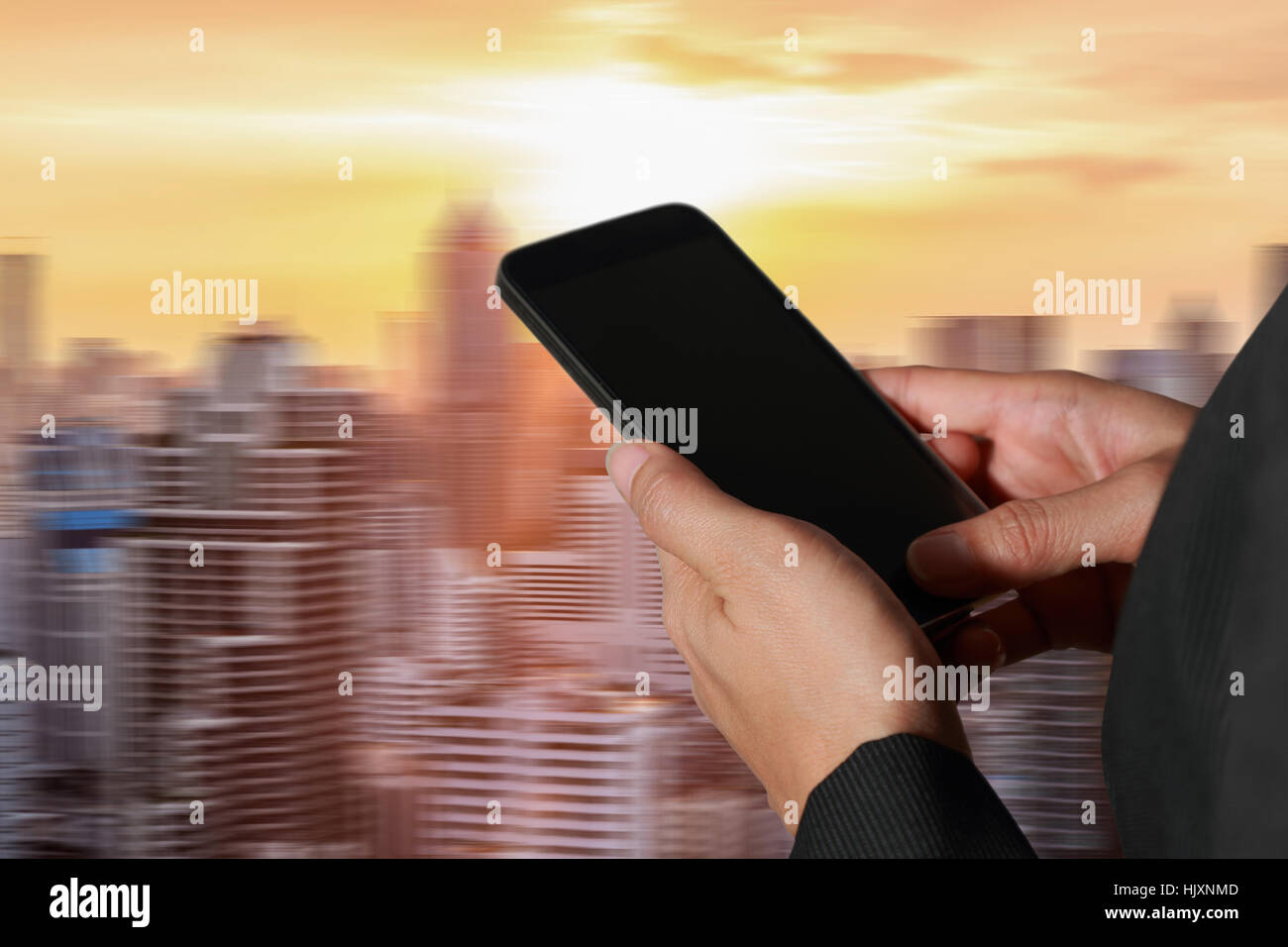 Mujer asidero smart phone, telefono movil en movimiento abstracto de la ciudad al atardecer como fondo el concepto de comunicación. Foto de stock