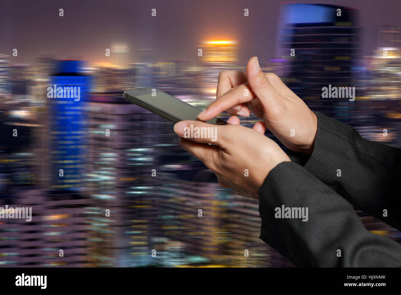 Mujer asidero y pantalla táctil de teléfono inteligente, móvil en movimiento abstracto de fondo ciudad de noche como el concepto de comunicación de alta velocidad. Foto de stock