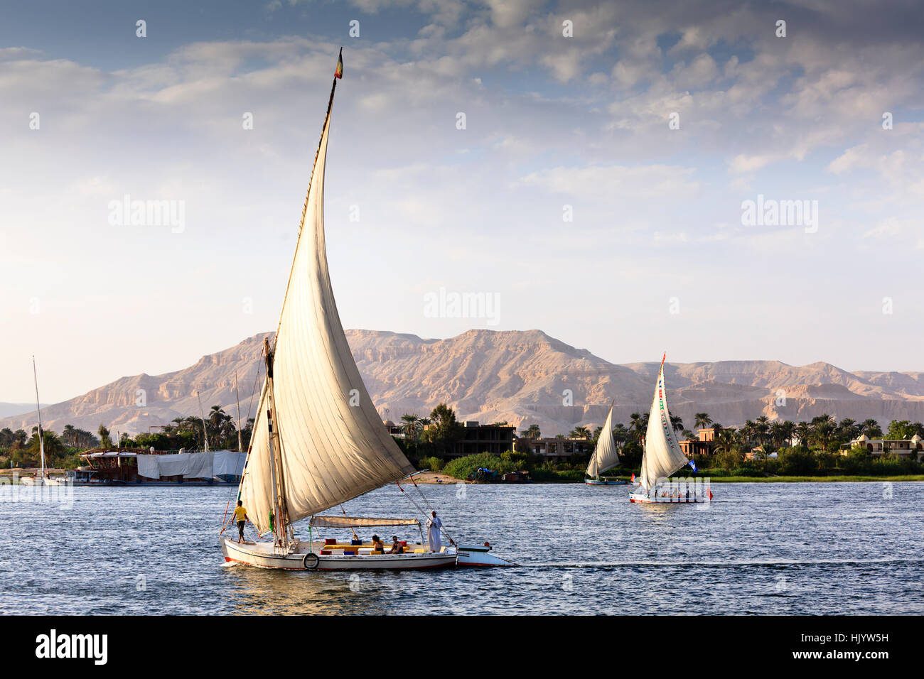 Feluchos veleros con turistas navegando por el río Nilo en Luxor al atardecer Foto de stock