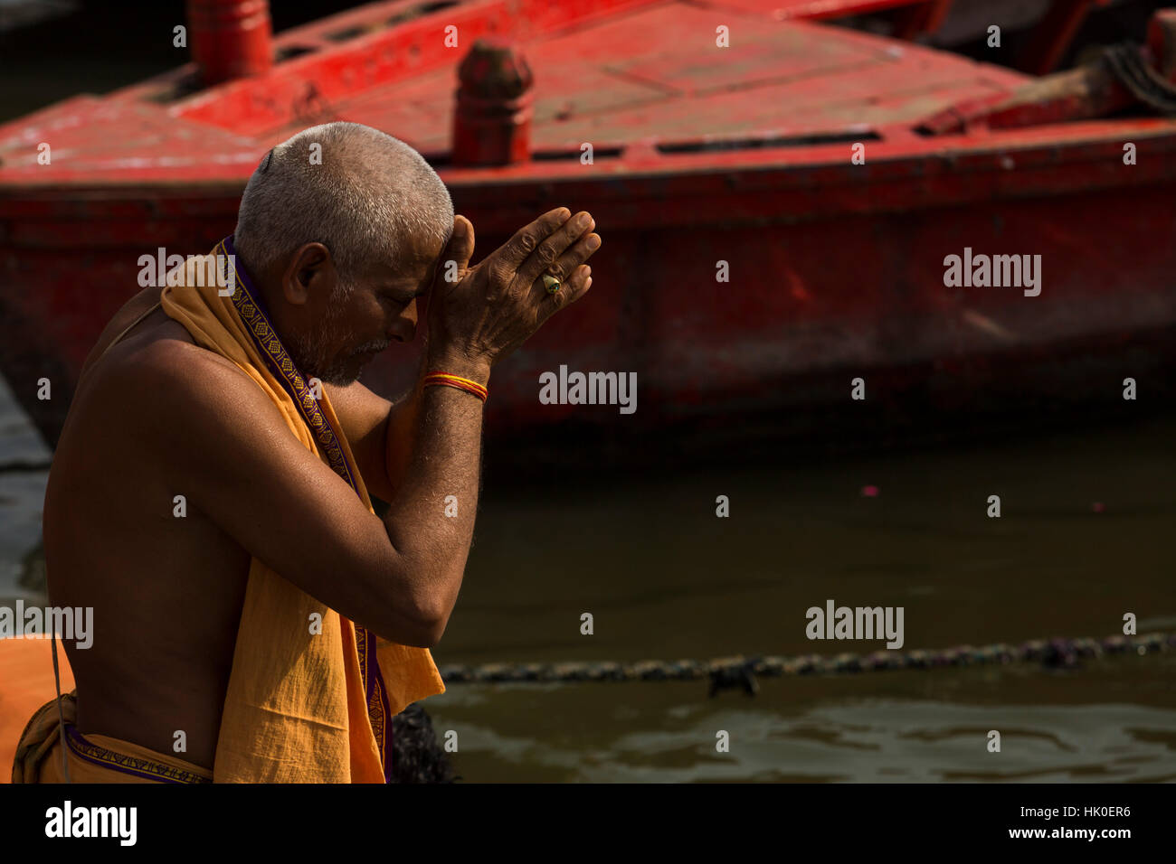 El hombre realiza una oración matutina en las sagradas aguas del río Ganges. Varanasi, India Foto de stock