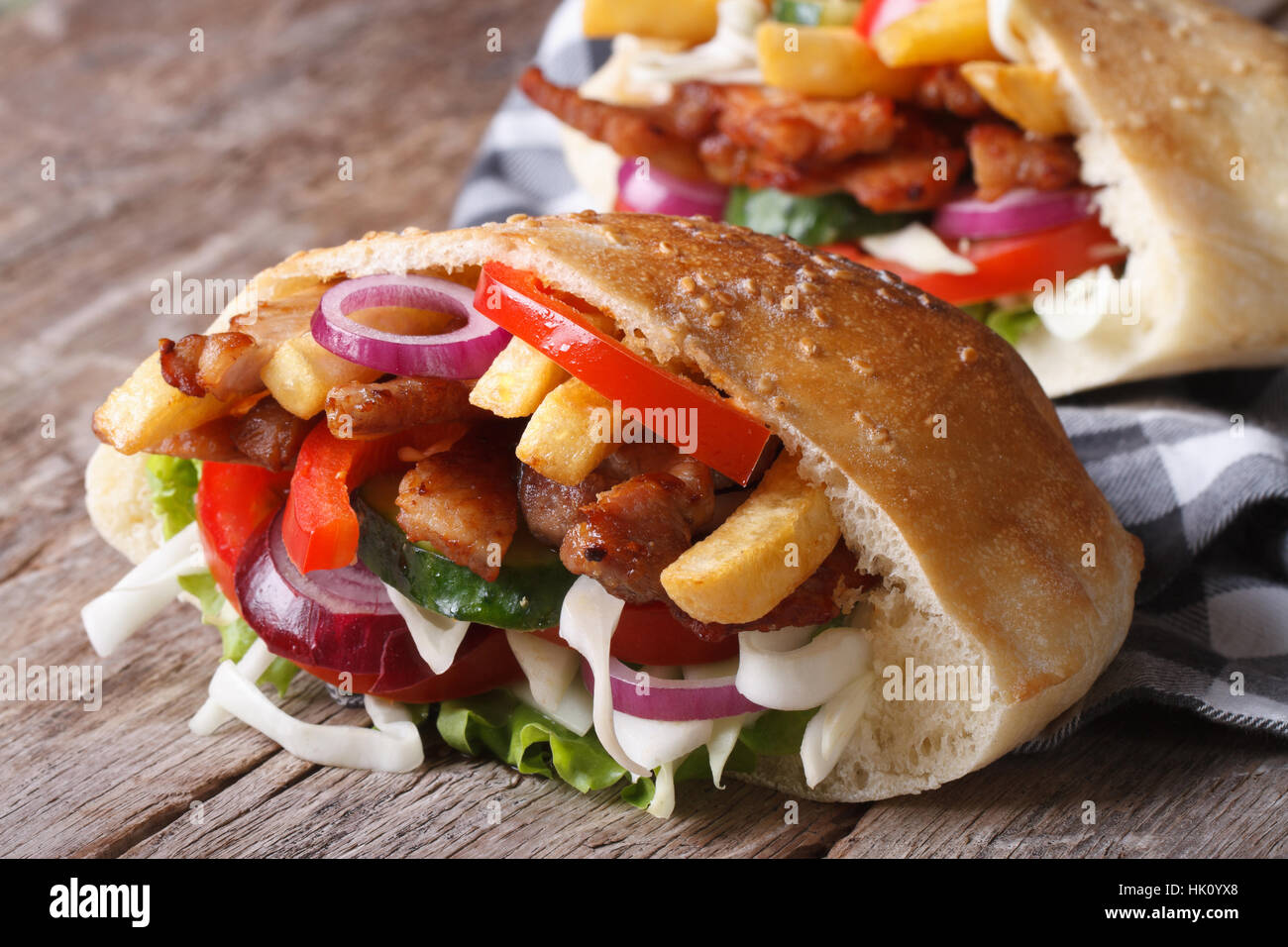 Dos kebab con carne, verduras y patatas fritas en pan de pita de cerca en una servilleta horizontal Foto de stock