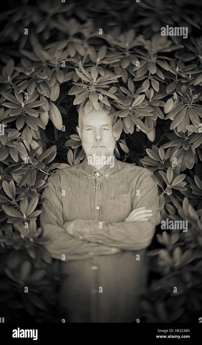 Retrato del hombre viejo rodeado por hojas de Bush. Concepto de la vejez y de la naturaleza. Jubilación y de confianza. Foto de stock