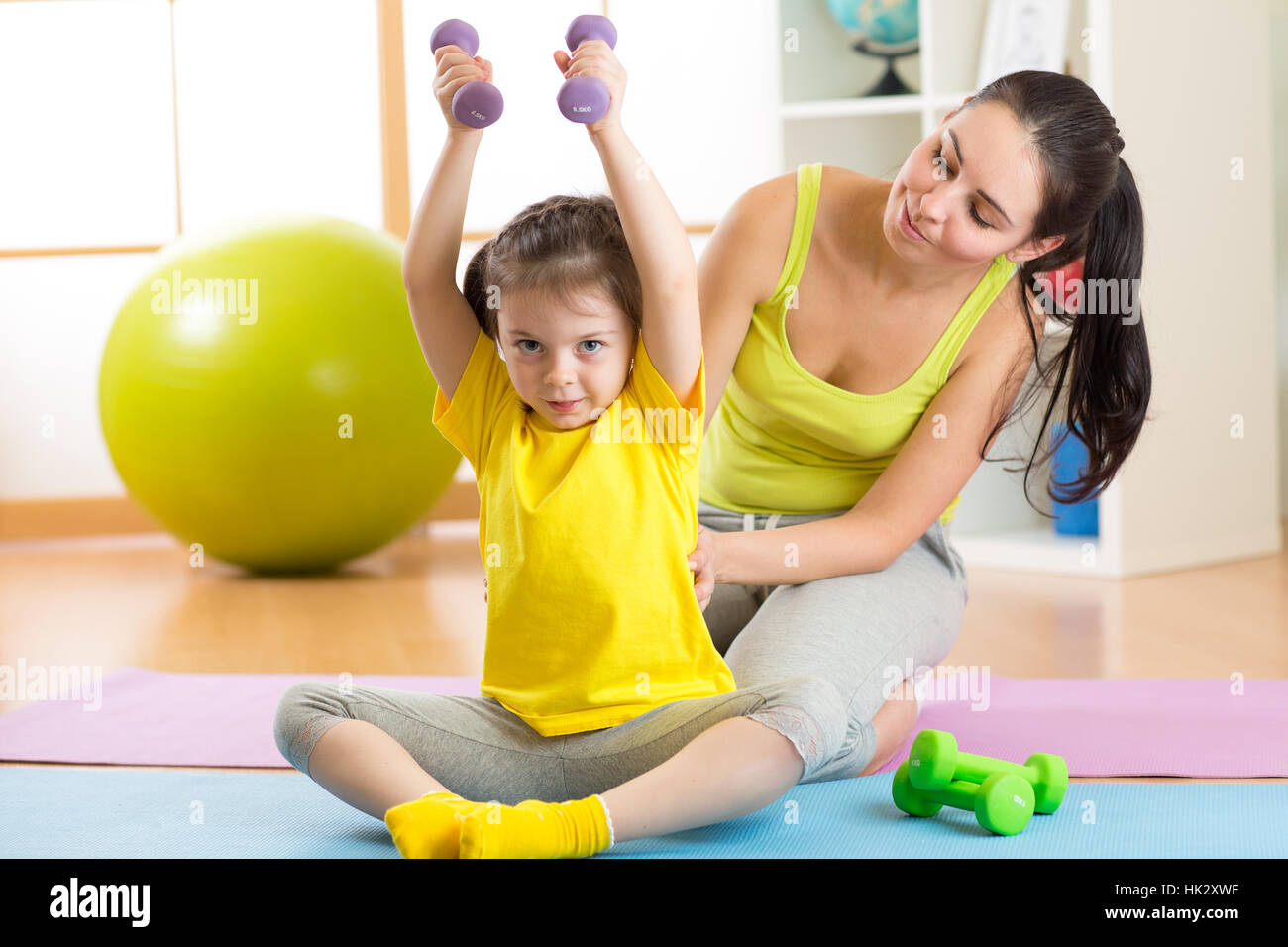 La hija de la madre y el niño de la familia participan en fitness, yoga, ejercicio en casa o en la sala de deportes Foto de stock