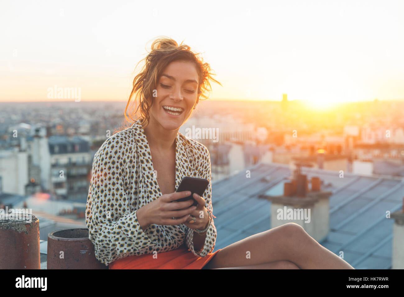 Mujer usando un teléfono inteligente sobre los tejados de París Foto de stock