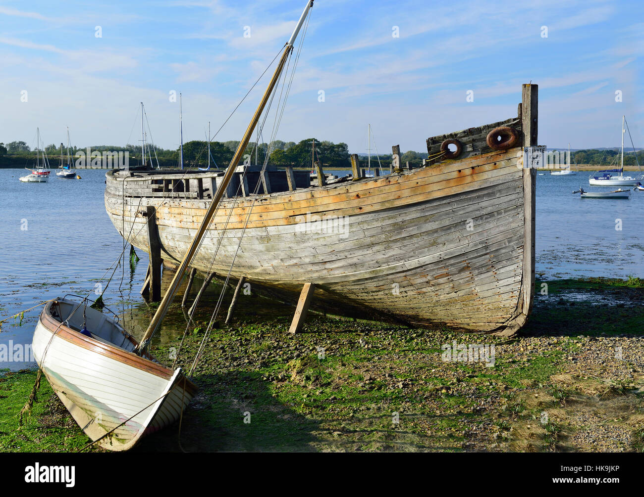 Casco antiguo de barcos en necesidad de reparación Para la venta al lado de  un bote a vela en marea baja en Dell Quay, en Chichester Harbor, West  Sussex, Inglaterra, Reino Unido