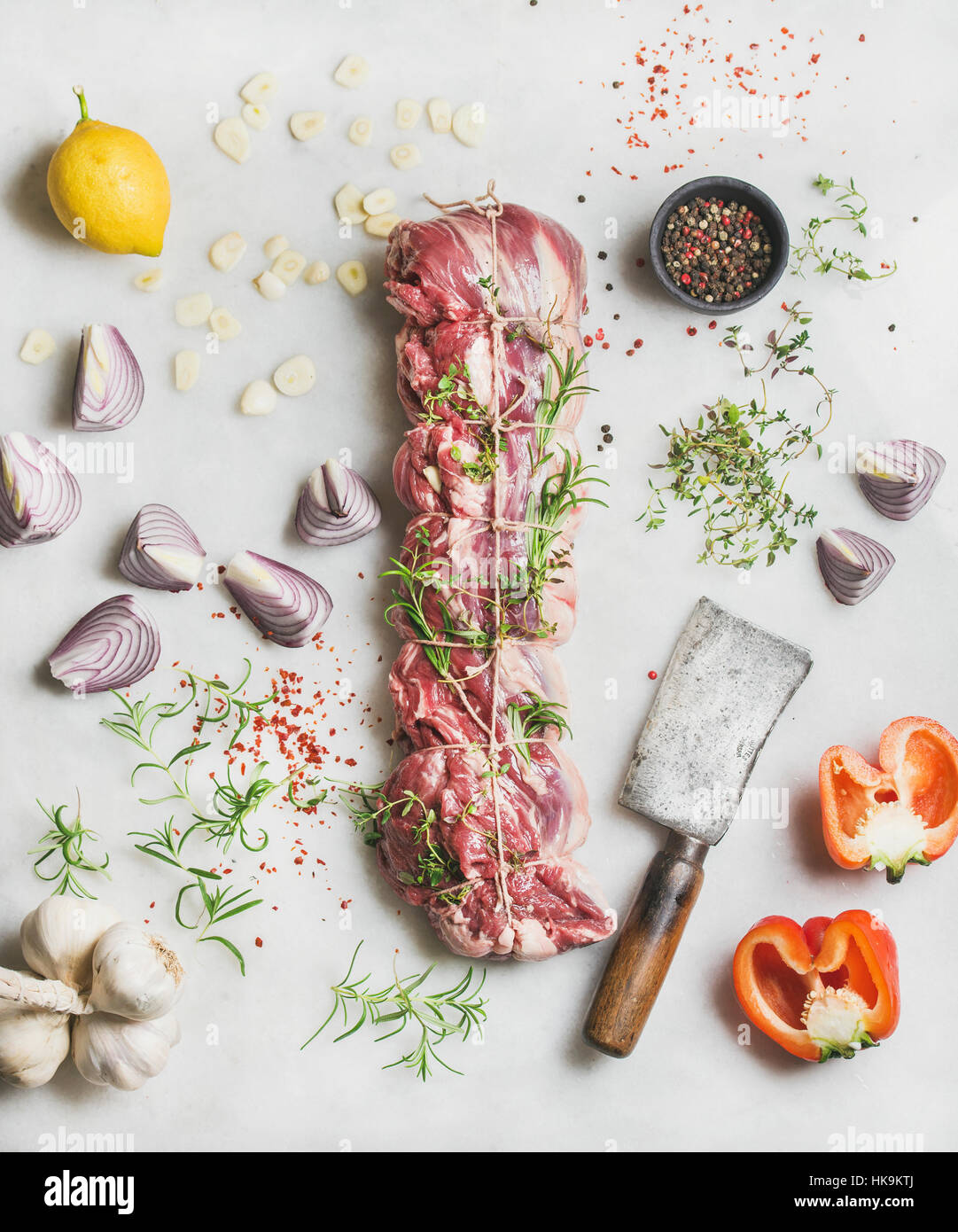 Las materias crudas y carne asada carne cortada con hierbas, verduras y especias sobre fondo de mármol gris claro, vista superior Foto de stock