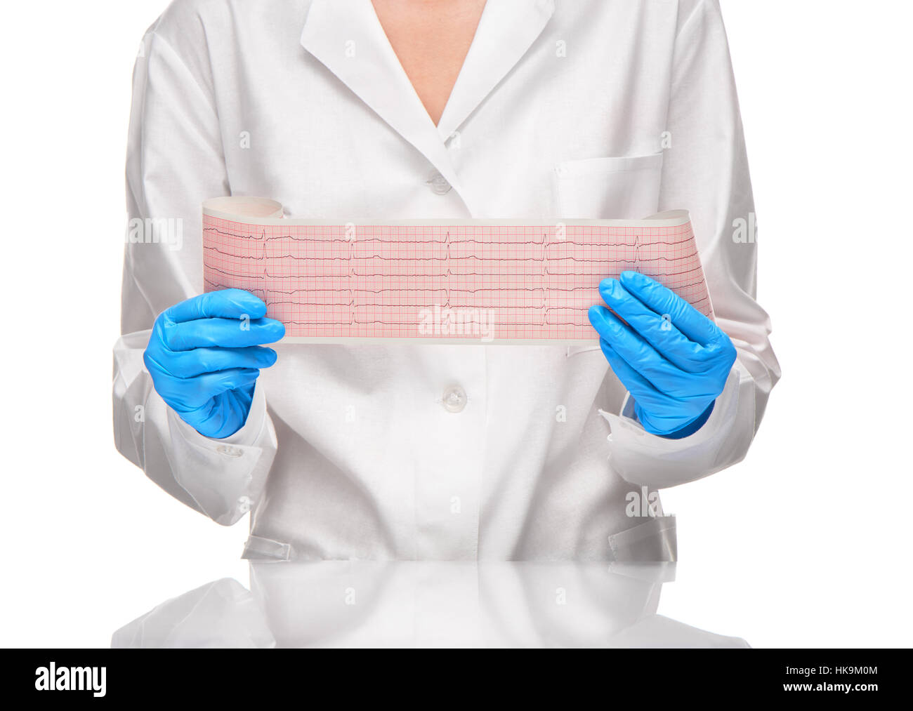 Doctora en vestido blanco y azul guantes manteniendo resultados de ECG en papel contra el fondo blanco. Foto de stock