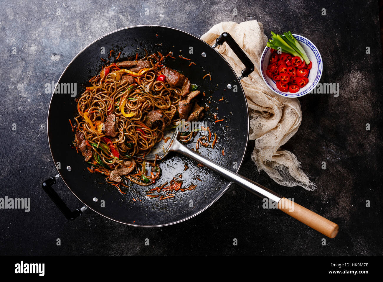 Stir-fry fideos soba con la carne y verduras en wok pan sobre fondo oscuro Foto de stock